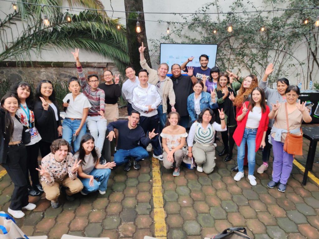 Grupo de jóvenes y facilitadores en el patio de una sede del programa, algunos con los brazos en alto